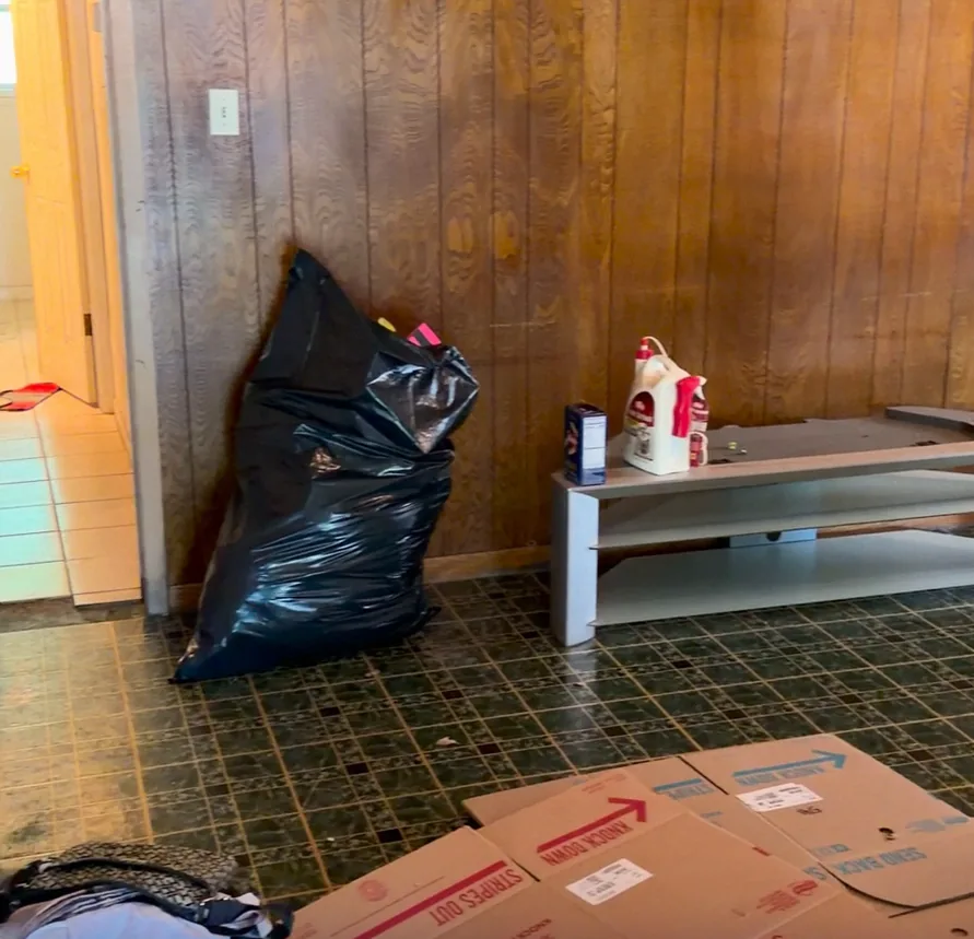A room in a house we bought as-is: trash bags, boxes and old paneling